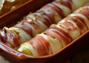 Endives cuite au four enveloppée de jambon disposée dans un plat